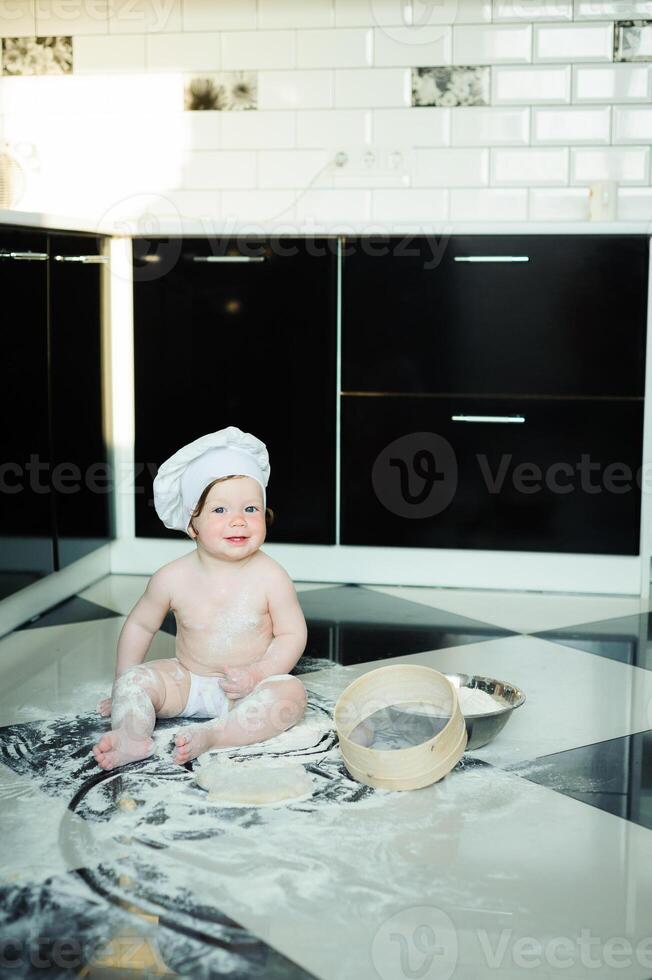 pequeno Garoto sentado em tapete dentro cozinha jogando com cozinhando potes. fofa Garoto cozinhando dentro cozinha às casa foto