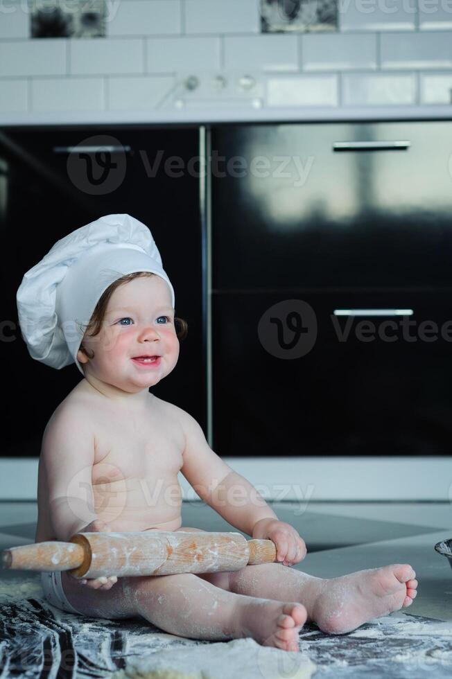 pequeno Garoto sentado em tapete dentro cozinha jogando com cozinhando potes. fofa Garoto cozinhando dentro cozinha às casa foto