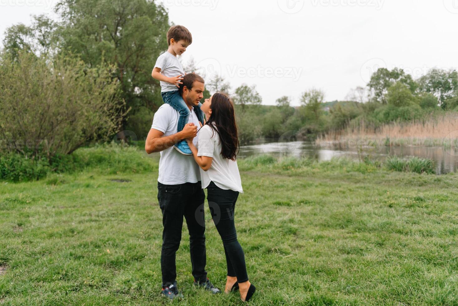 feliz família mãe pai e criança filho em natureza em pôr do sol. mãe, Papai e criança rindo e abraçando, desfrutando natureza fora. ensolarado dia, Boa humor. conceito do uma feliz família. foto