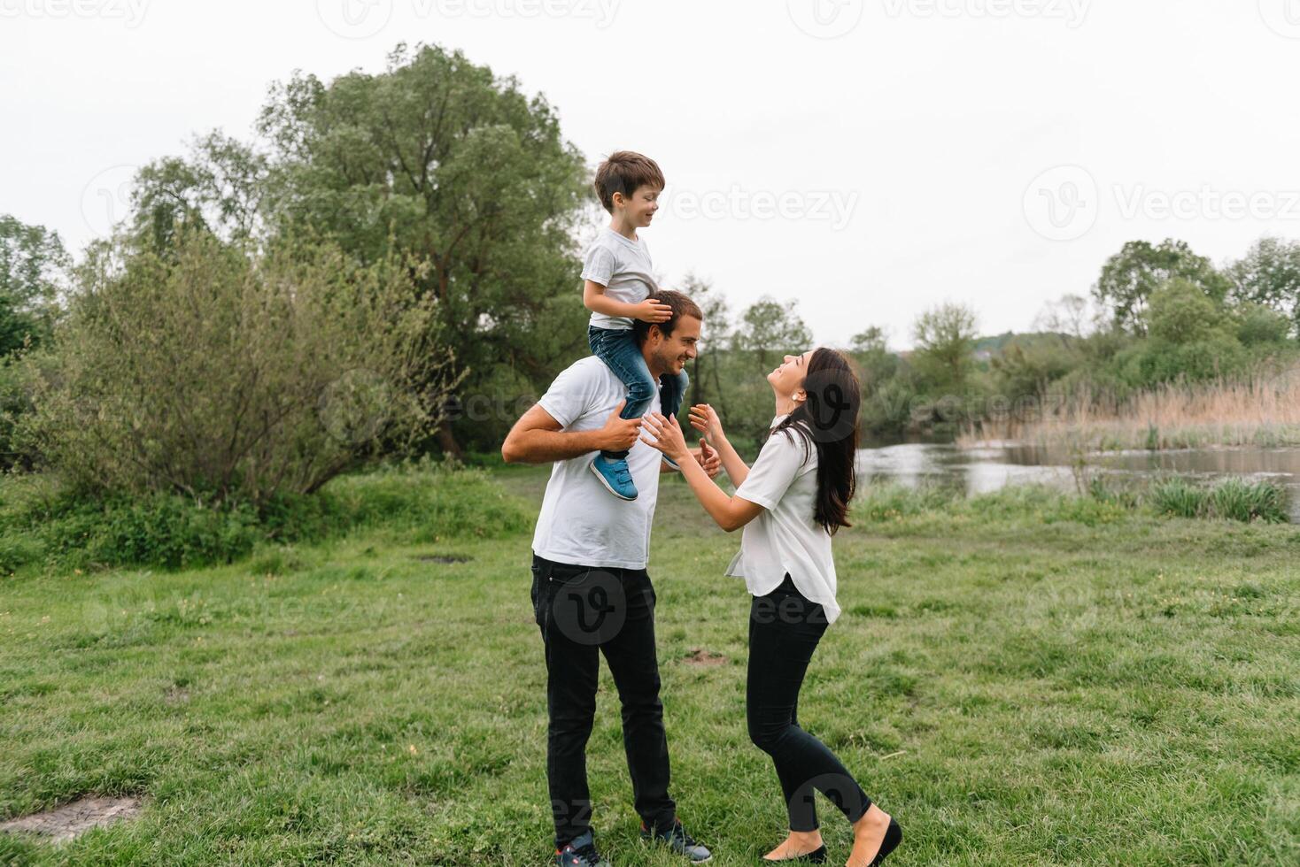 feliz família mãe pai e criança filho em natureza em pôr do sol. mãe, Papai e criança rindo e abraçando, desfrutando natureza fora. ensolarado dia, Boa humor. conceito do uma feliz família. foto