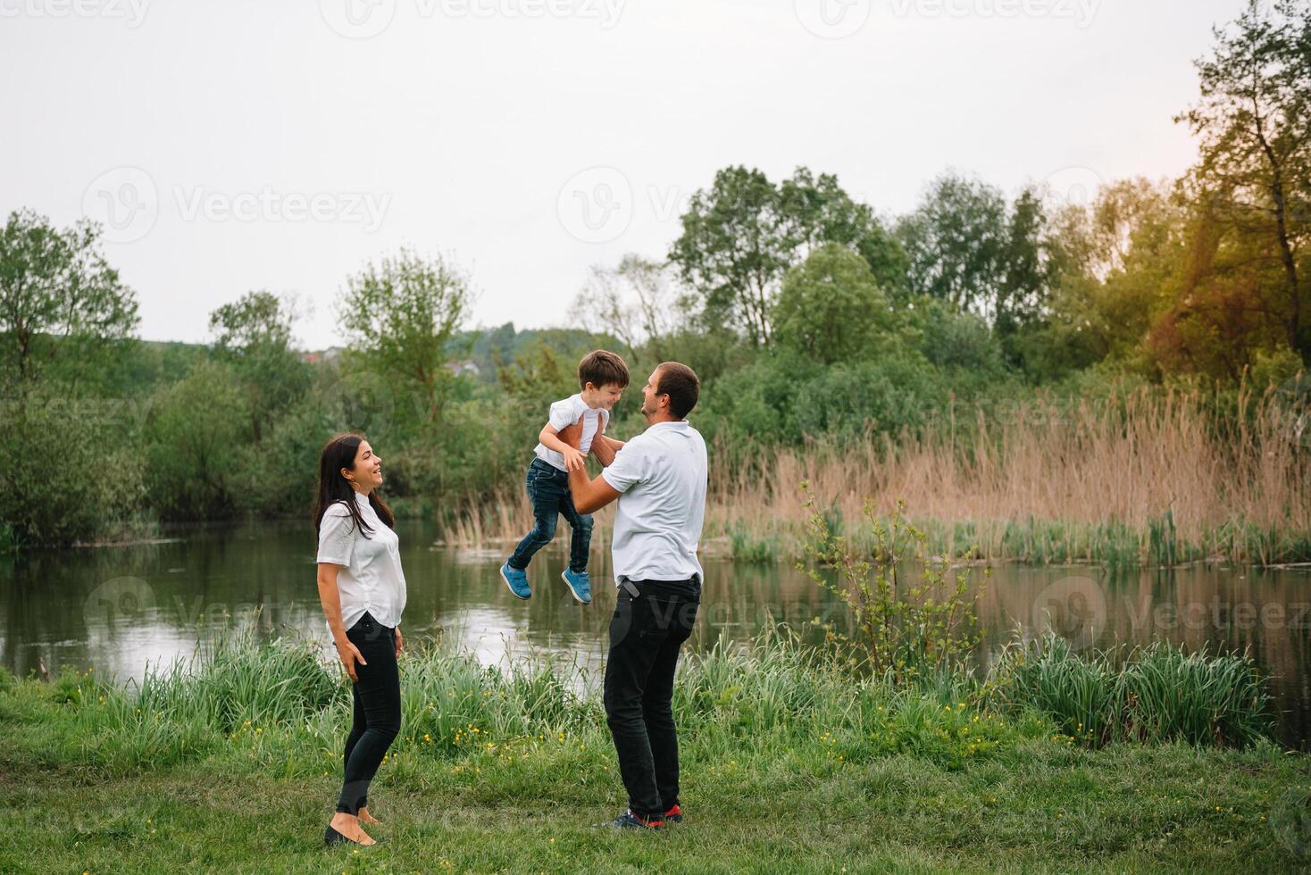 feliz família mãe pai e criança filho em natureza em pôr do sol. mãe, Papai e criança rindo e abraçando, desfrutando natureza fora. ensolarado dia, Boa humor. conceito do uma feliz família. foto