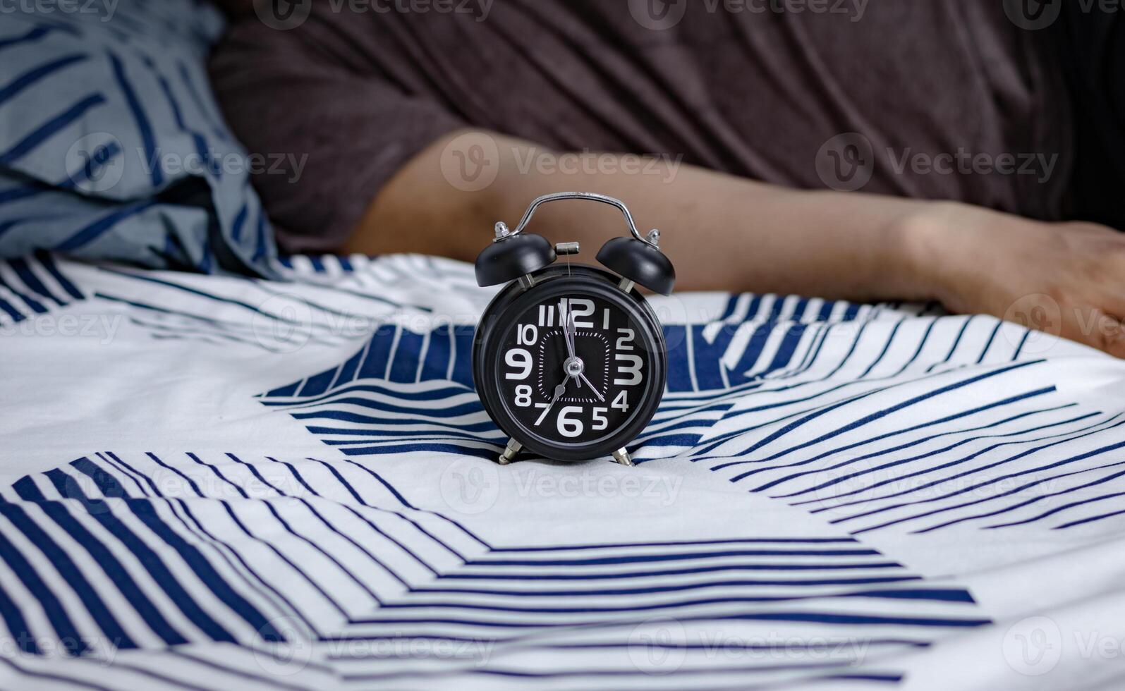data limite e Tempo gestão conceito. Preto alarme relógio em cama com preguiçoso pessoas ainda dormindo dentro a manhã foto