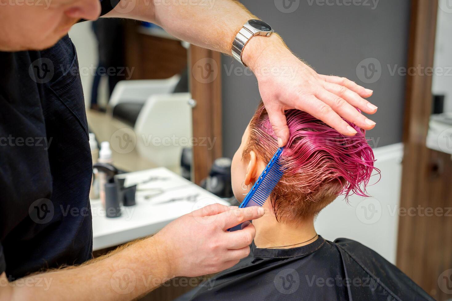 mãos do cabeleireiro pentear cabelo fazer curto Rosa Penteado para uma jovem caucasiano mulher dentro uma beleza salão. foto