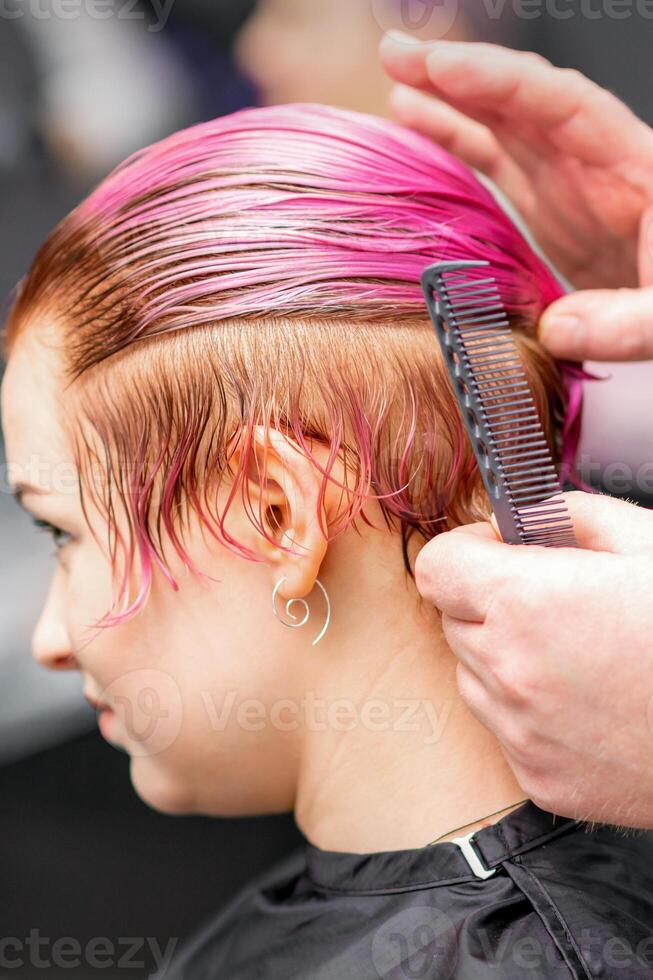 estilo fêmea cabelo. masculino cabeleireiro faz Penteado para uma jovem mulher dentro uma beleza salão. foto