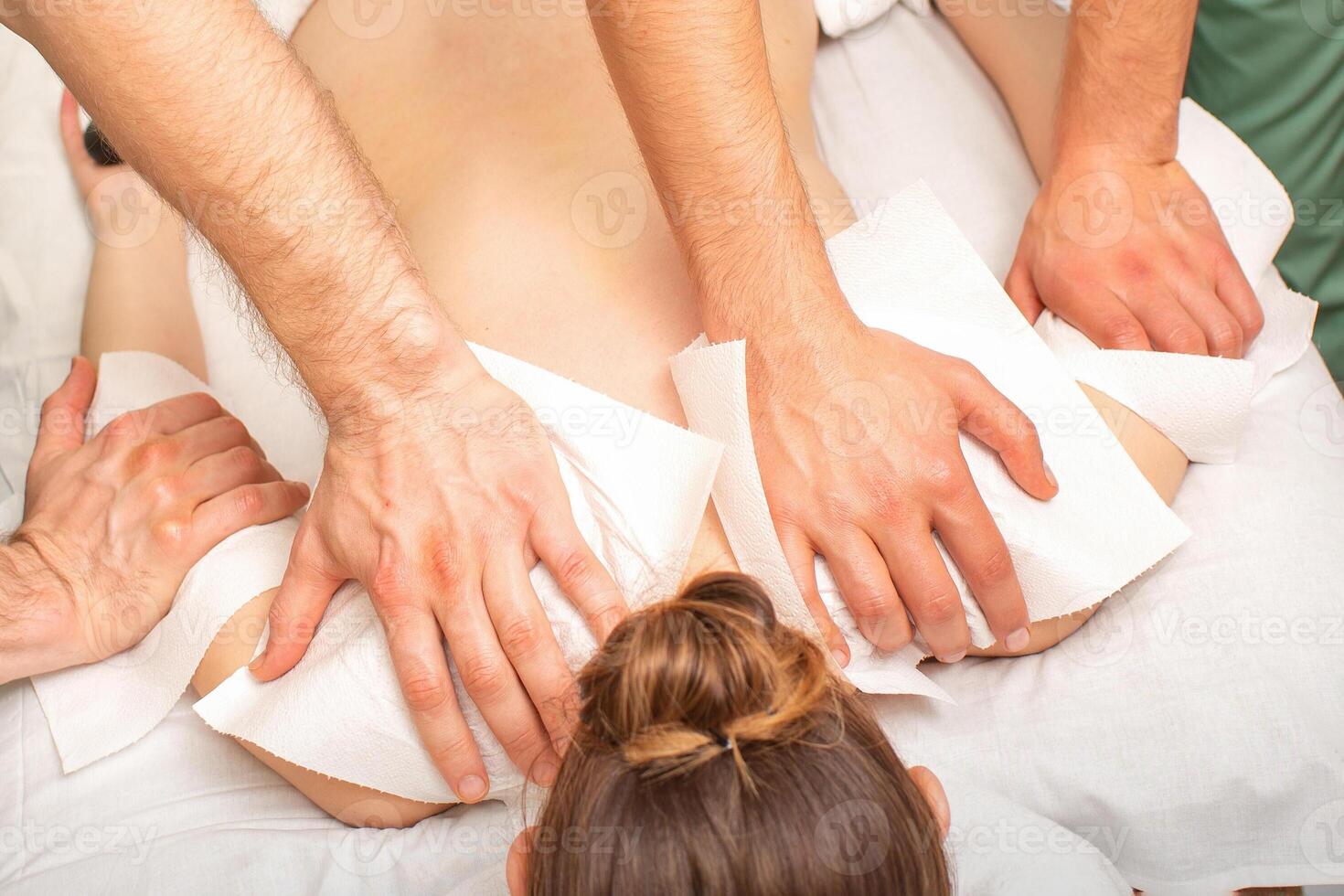 costas massagem com quatro mãos dentro a spa salão. dois massagem terapeutas faço uma costas massagem para uma jovem mulher. foto