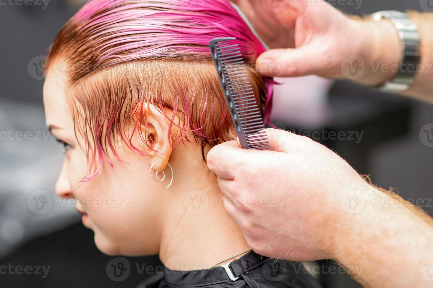 estilo fêmea cabelo. masculino cabeleireiro faz Penteado para uma jovem mulher dentro uma beleza salão. foto