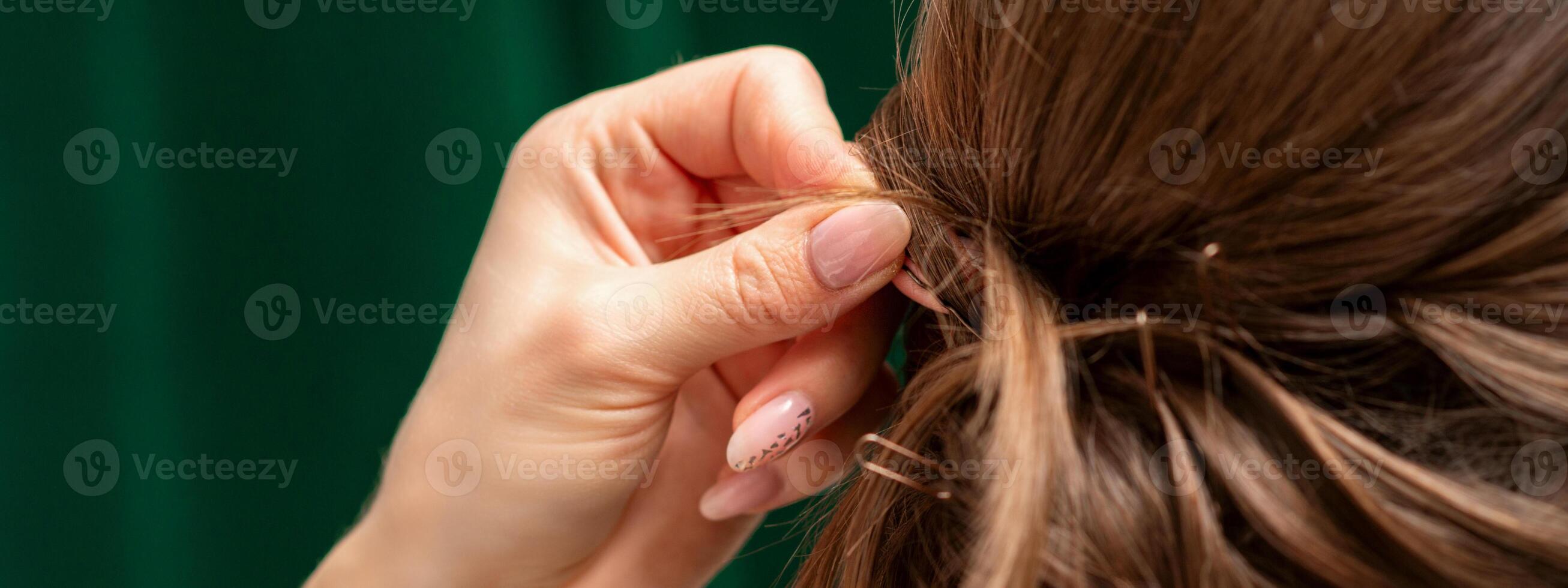 cabeleireiro faz penteados para uma jovem mulher dentro beleza salão fechar acima. foto