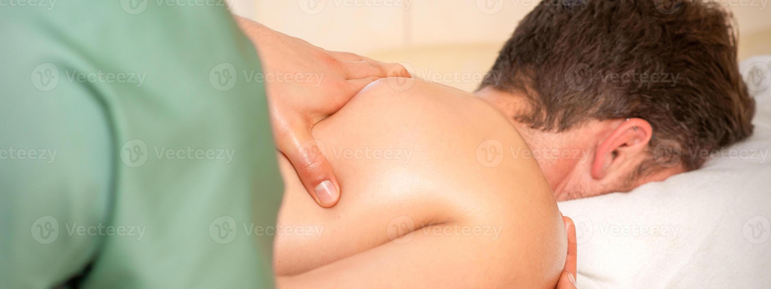 fisioterapeuta dando ombro massagem para homem dentro hospital. foto