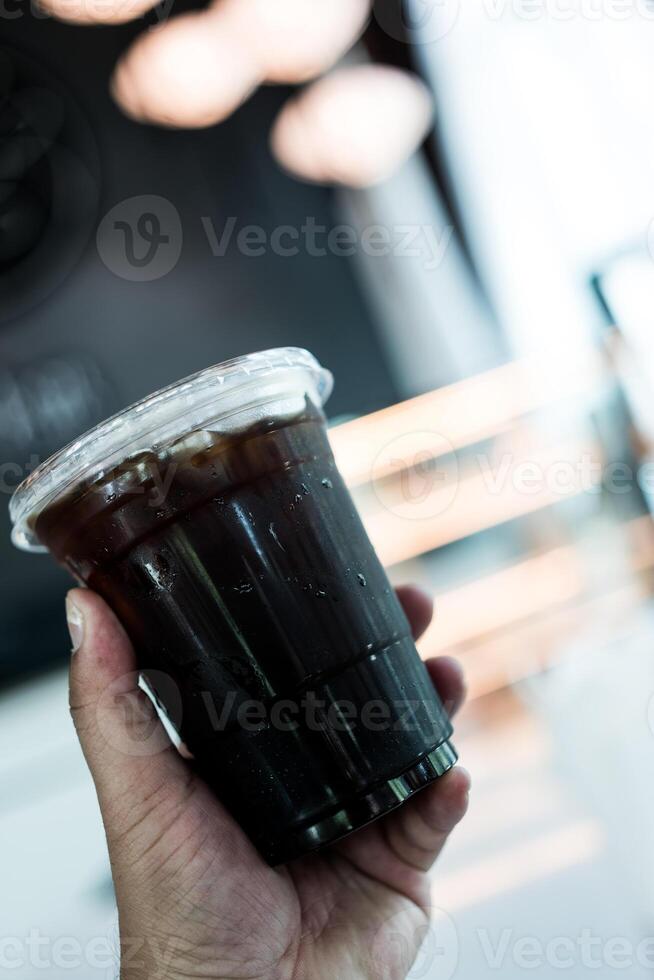 alguém segurando uma plástico copo do gelo Preto café. foto