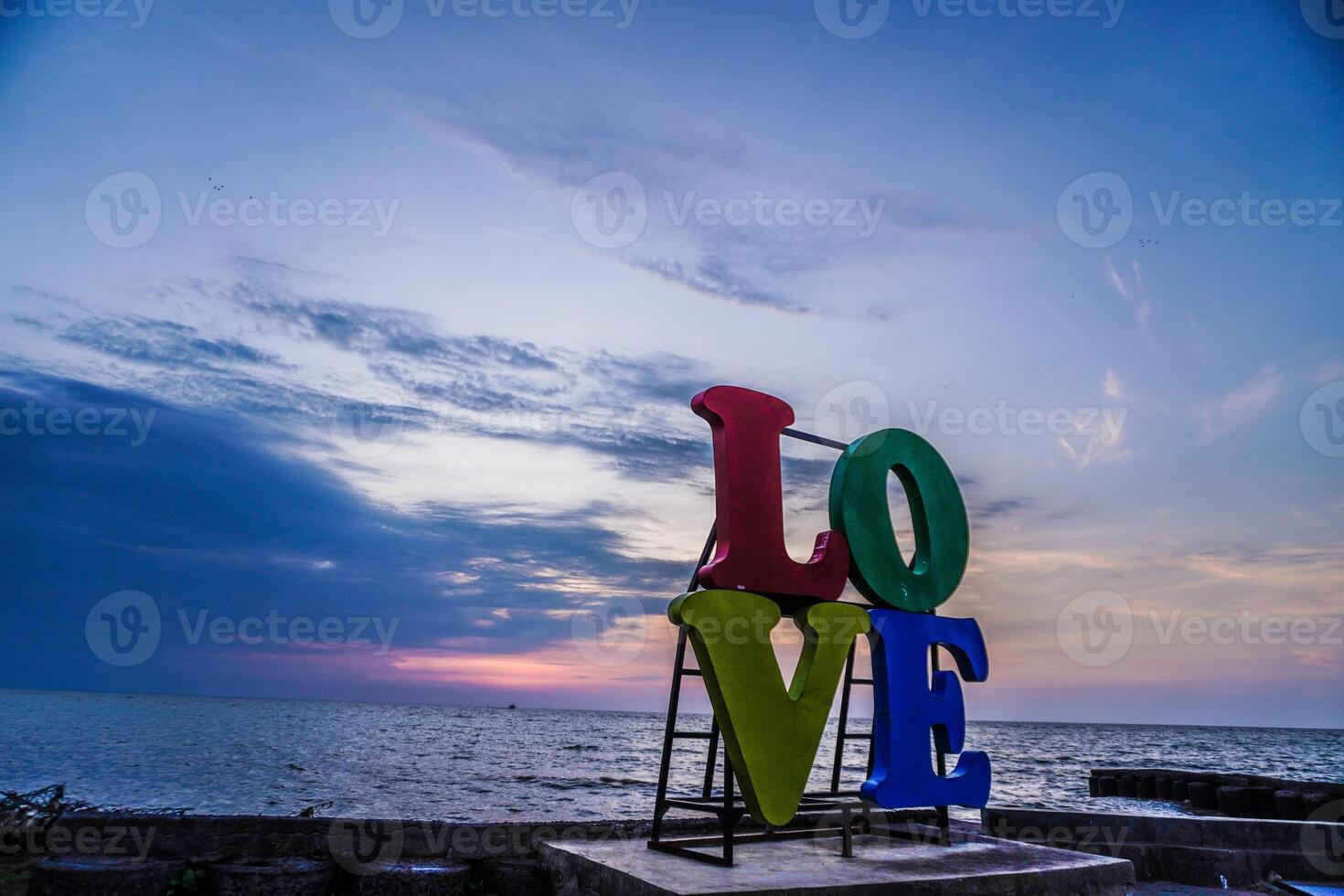 fechar-se Visão do a palavra amor colocada em a litoral contra uma pôr do sol céu com esvaziar espaço para fotocópia. foto