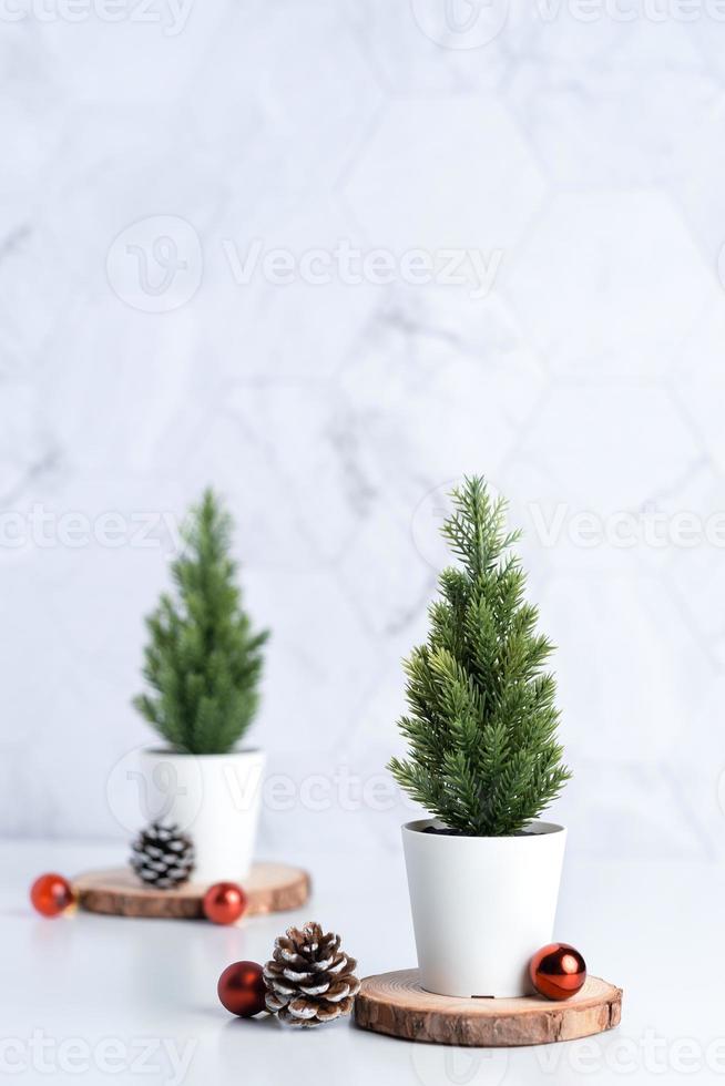 árvore de natal com pinha, decoração bola de natal em tronco de madeira na mesa branca foto