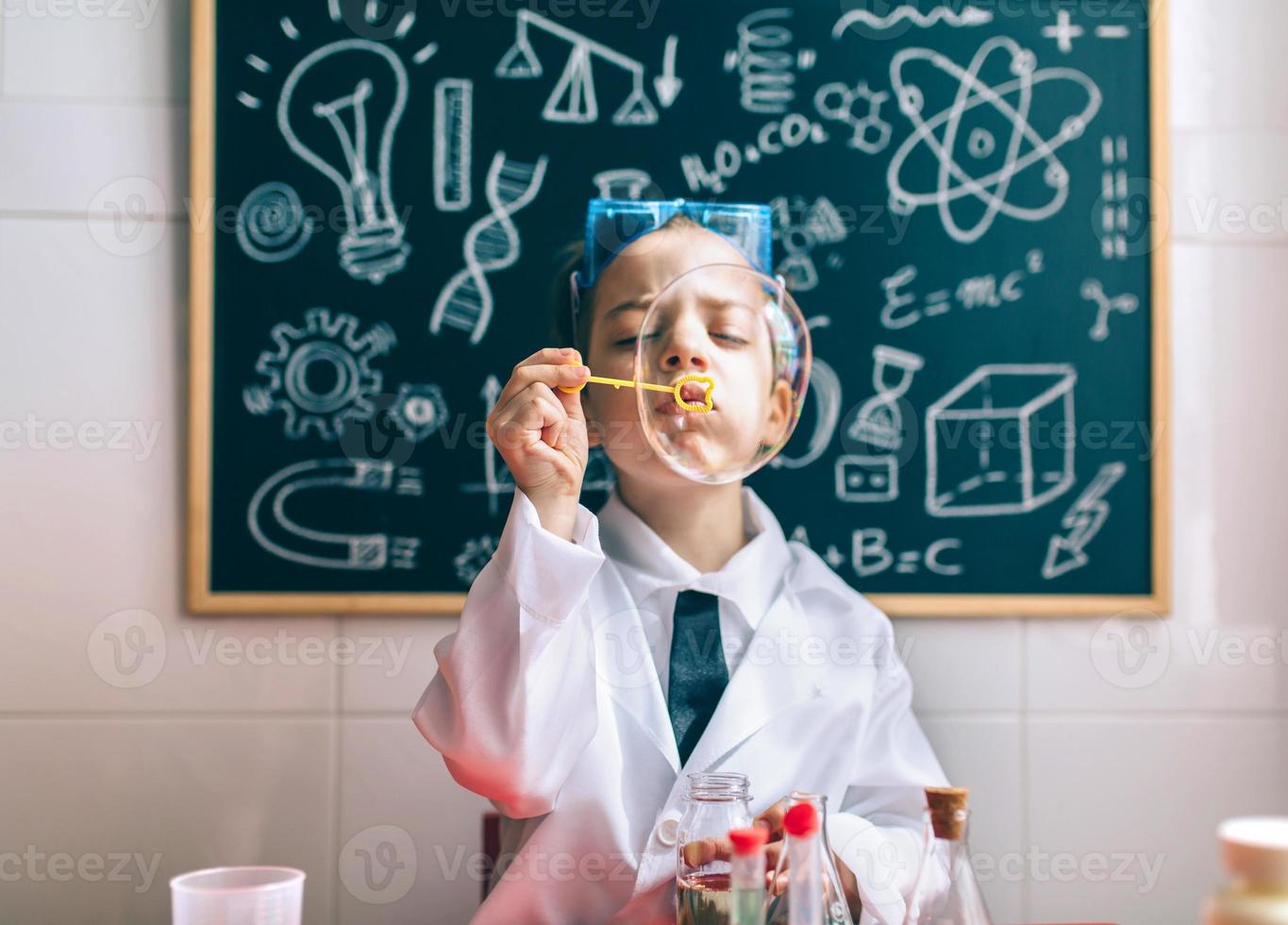 garoto fazendo bolhas de sabão contra o quadro-negro desenhado foto