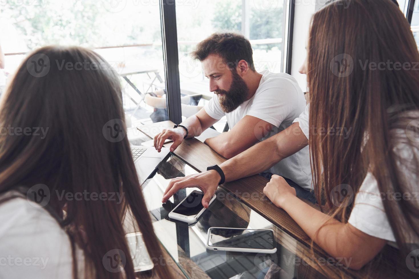 um grupo de jovens com gadgets e um laptop organizam um brainstorm e se comunicam entre si. o conceito de desenvolver um jovem negócio foto