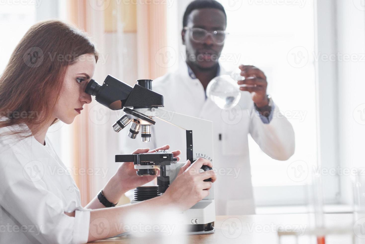 assistente de laboratório com lâmpada de vidro de laboratório de microscópio com produtos químicos. foto