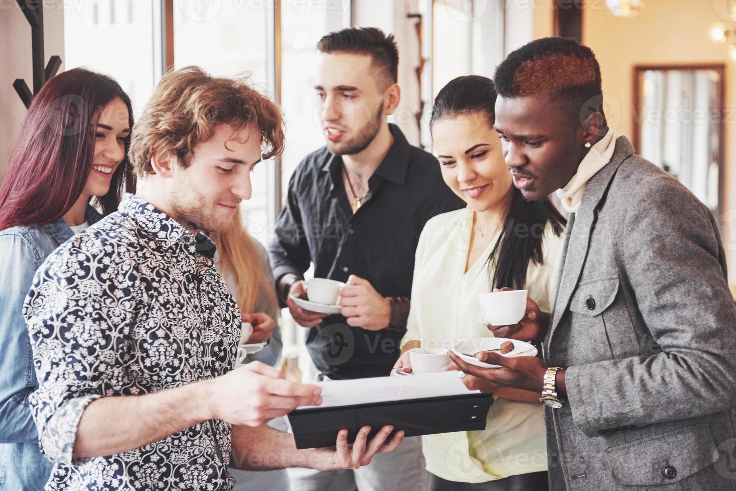 empresários de sucesso estão usando gadgets, conversando e sorrindo durante a pausa para o café no escritório foto