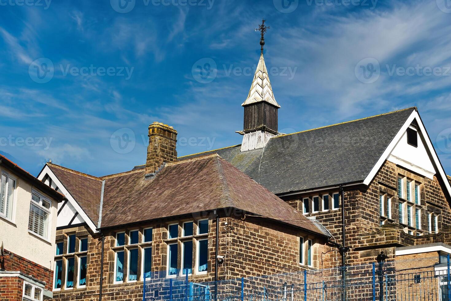 tradicional tijolo escola construção com uma pináculo contra uma azul céu com fino nuvens dentro Harrogate, norte Iorque. foto