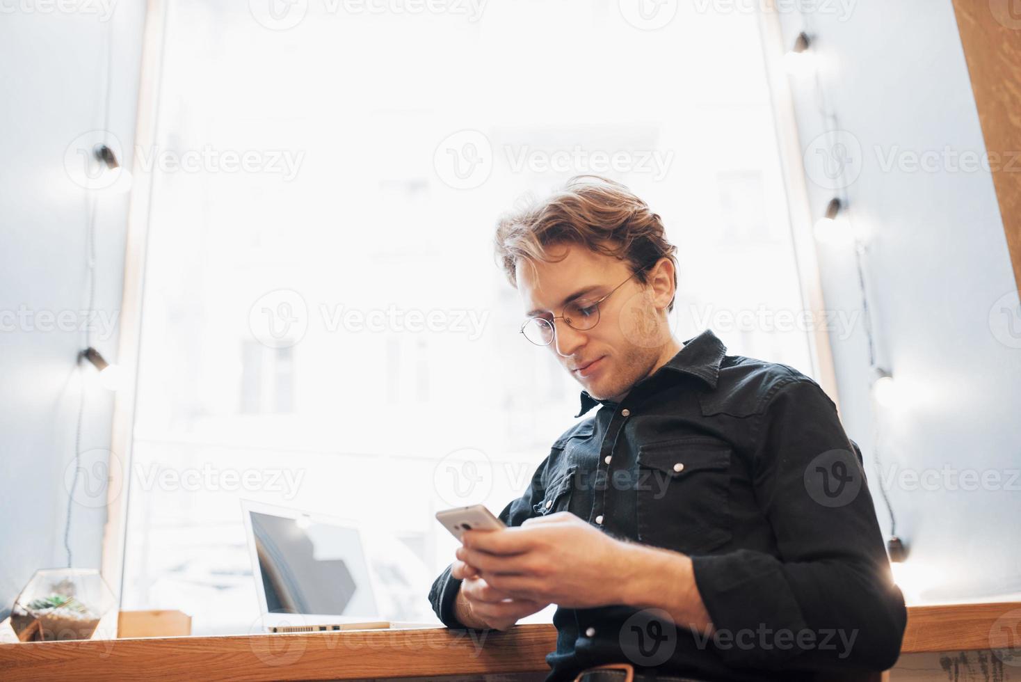 jovem profissional relaxado navegando na internet em seu laptop em um café foto