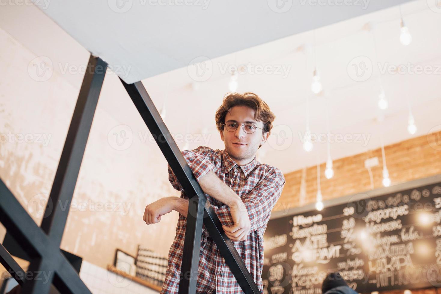 jovem pensativo está sentado na confeitaria. ela está bebendo café enquanto espera por alguém foto