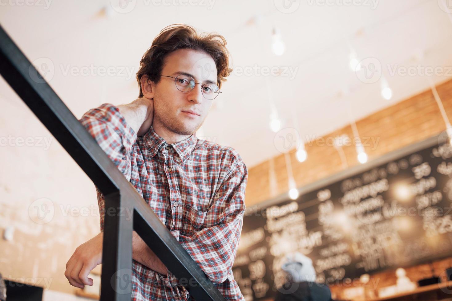 jovem pensativo está sentado na confeitaria. ela está bebendo café enquanto espera por alguém foto