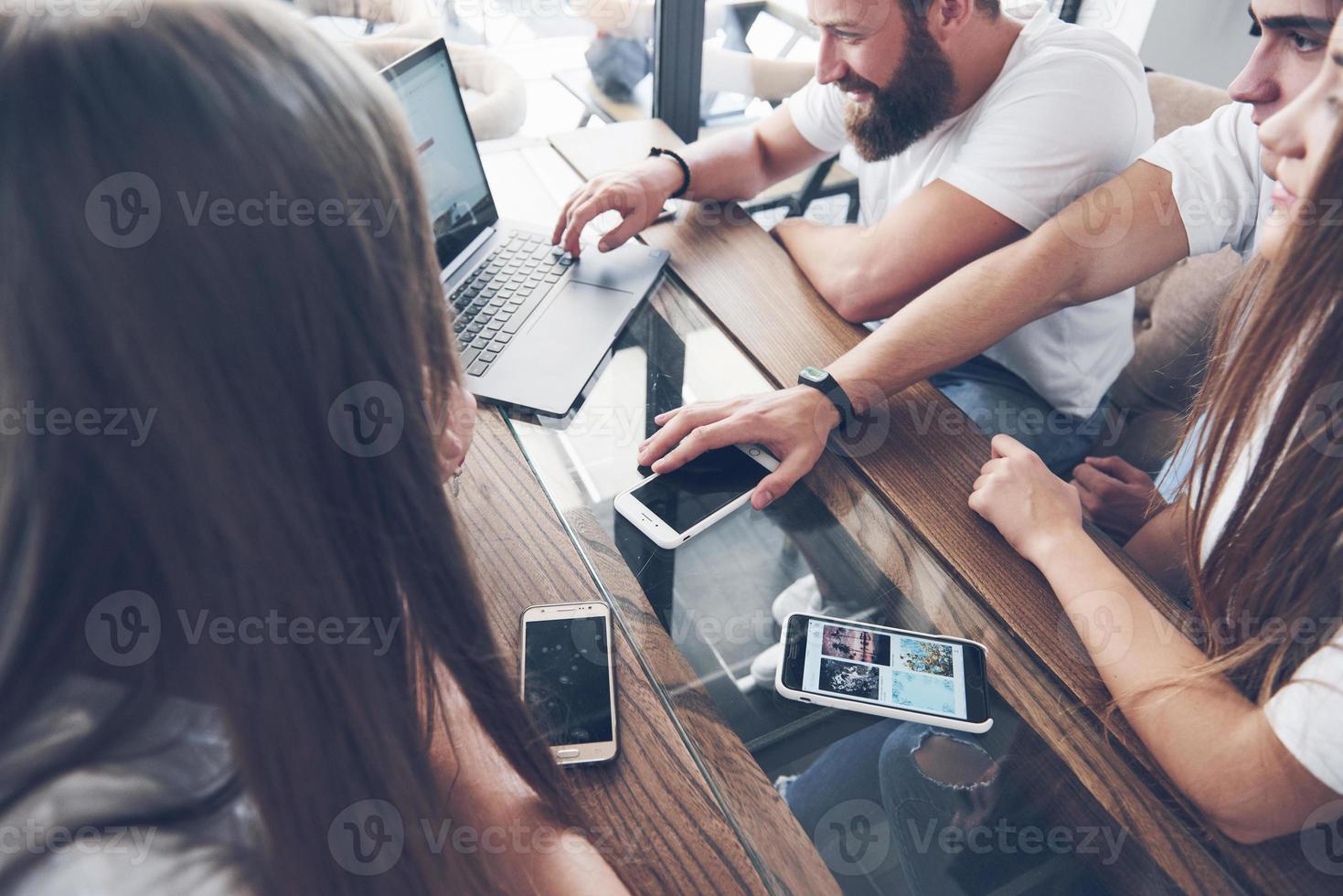 um grupo de jovens com gadgets e um laptop organizam um brainstorm e se comunicam entre si. o conceito de desenvolver um jovem negócio foto