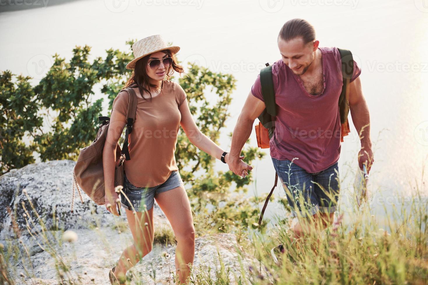 dois turistas homem e mulher com mochilas sobem ao topo da montanha e aproveitando o nascer do sol. conceito de férias de aventura de estilo de vida de viagens foto