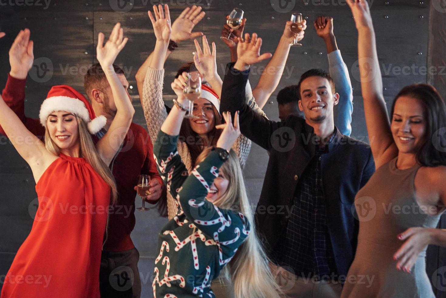 festa com amigos. eles amam o natal. grupo de jovens alegres carregando estrelinhas e taças de champanhe, dançando na festa de ano novo e parecendo feliz. conceitos sobre estilo de vida de união foto