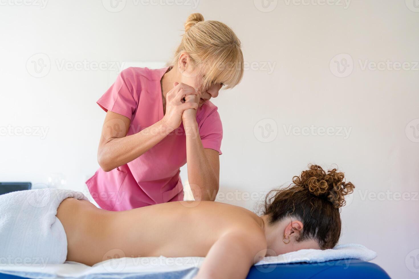profissional fêmea osteopata fazendo fisica terapia com cotovelo em cliente foto