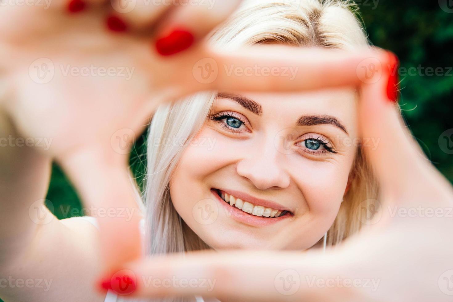 mulher sorrindo fazendo moldura com as mãos e os dedos foto