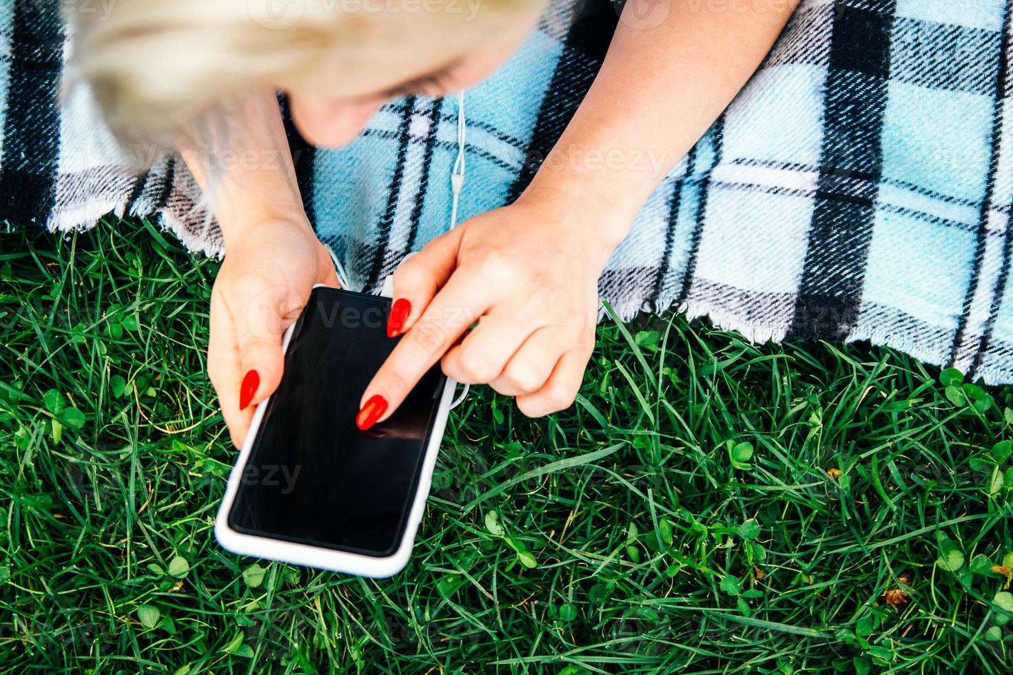 mulher com fones de ouvido e smartphone nas mãos sobre fundo verde foto