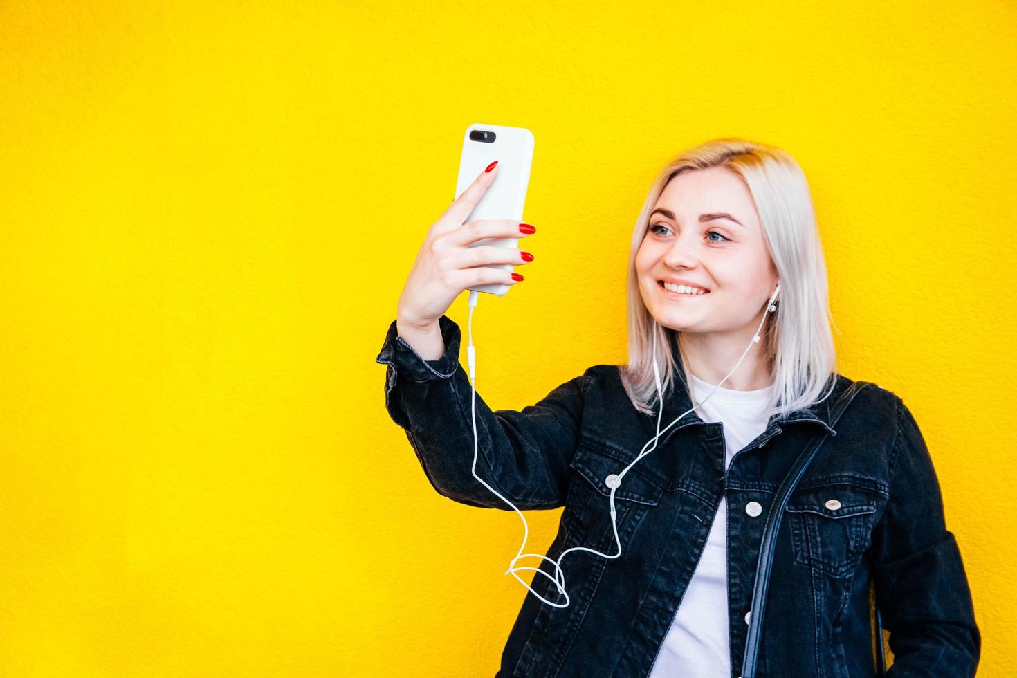 mulher com fones de ouvido e smartphone nas mãos sobre fundo amarelo foto