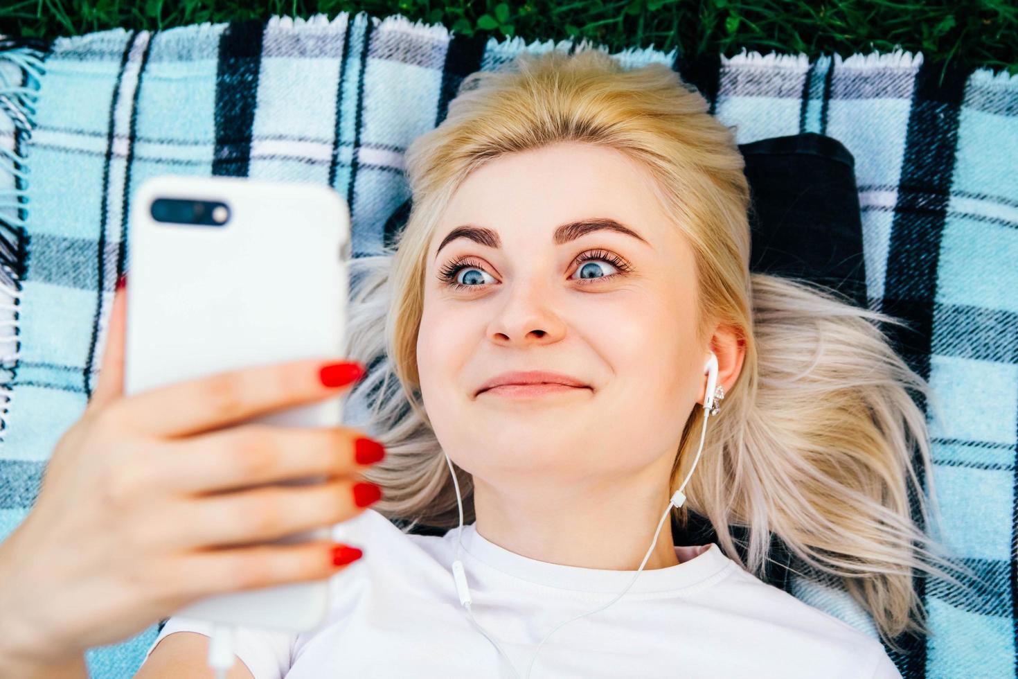 mulher com fones de ouvido e smartphone nas mãos mentindo foto