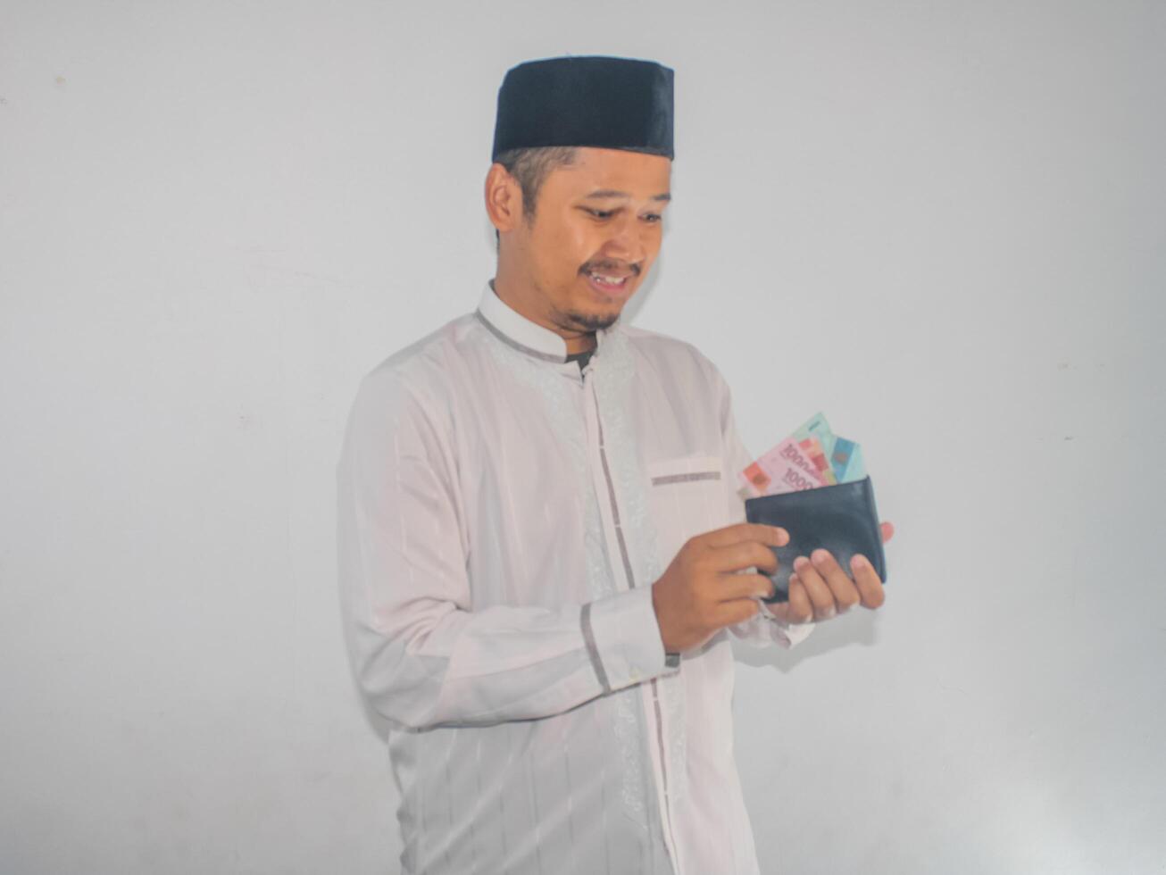 lado Visão do muçulmano ásia homem sorridente feliz quando levando dinheiro a partir de dentro dele carteira foto