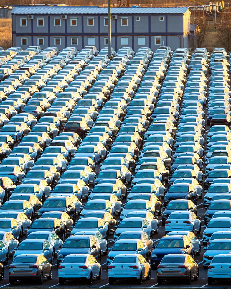 Volkswagen grupo russo, Rússia, Kaluga - novembro 17, 2020 linhas do uma Novo carros estacionado dentro uma distribuição Centro em uma ensolarado outono manhã e uma carro fábrica edifícios. foto
