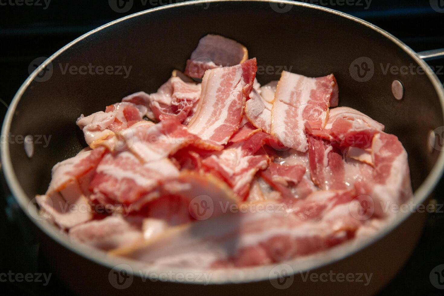 cozinhando bacon em uma fogão topo foto