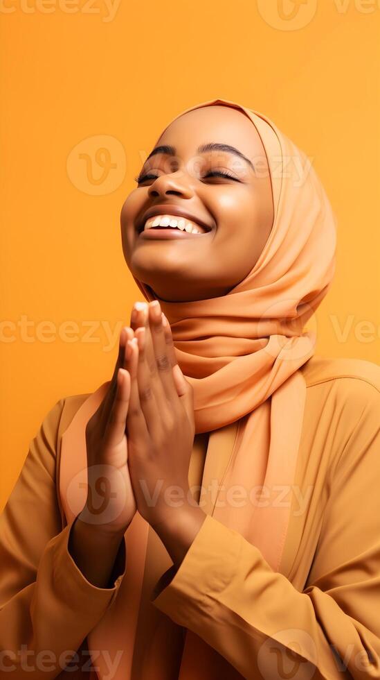 africano mulher vestindo cachecol é Rezar e sorridente em Castanho fundo foto