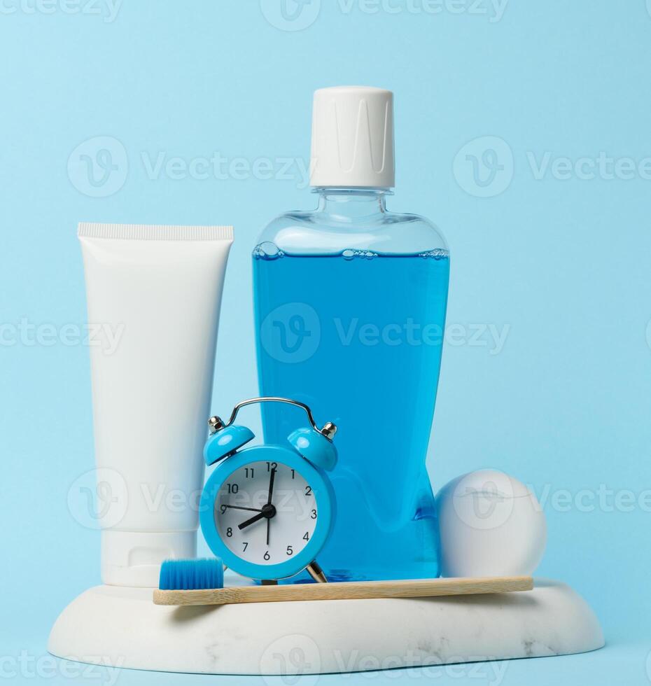 enxaguatório bucal e pasta de dentes tubo, alarme relógio em azul fundo, oral higiene foto