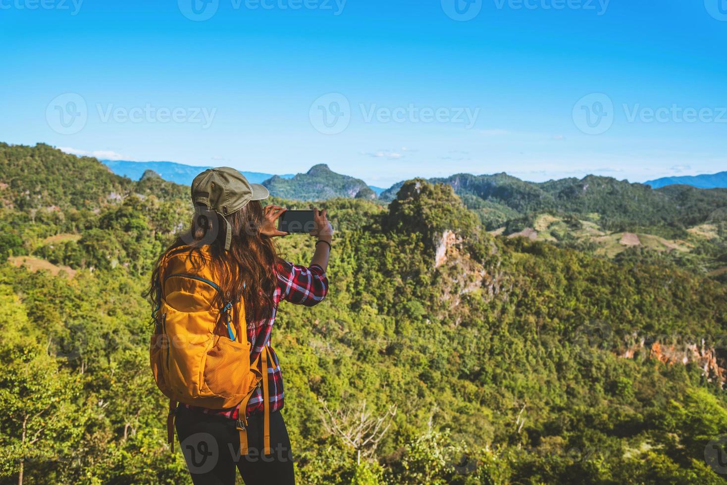 a mulher em pé no ponto de vista. divirta-se fotografando a beleza natural das montanhas. foto