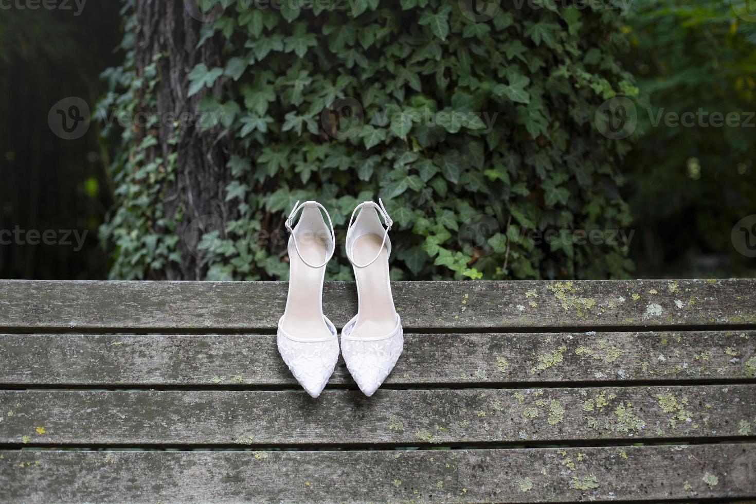 sapatos de casamento brancos com renda e salto em velhas tábuas de madeira foto