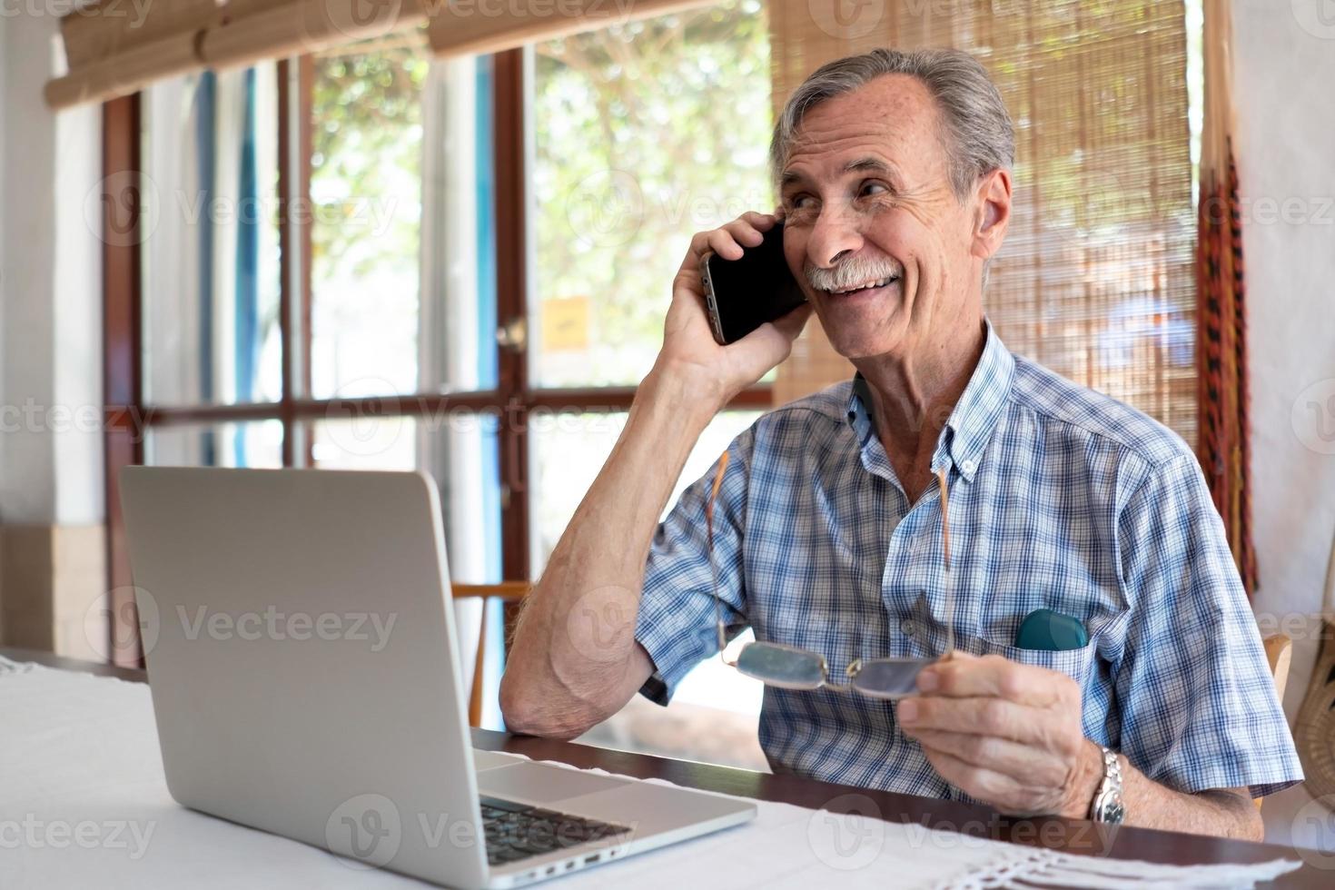 homem maduro usando telefone celular e laptop foto