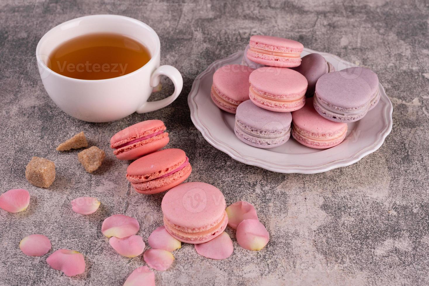 lindos macaroons saborosos cor de rosa em um fundo de concreto foto