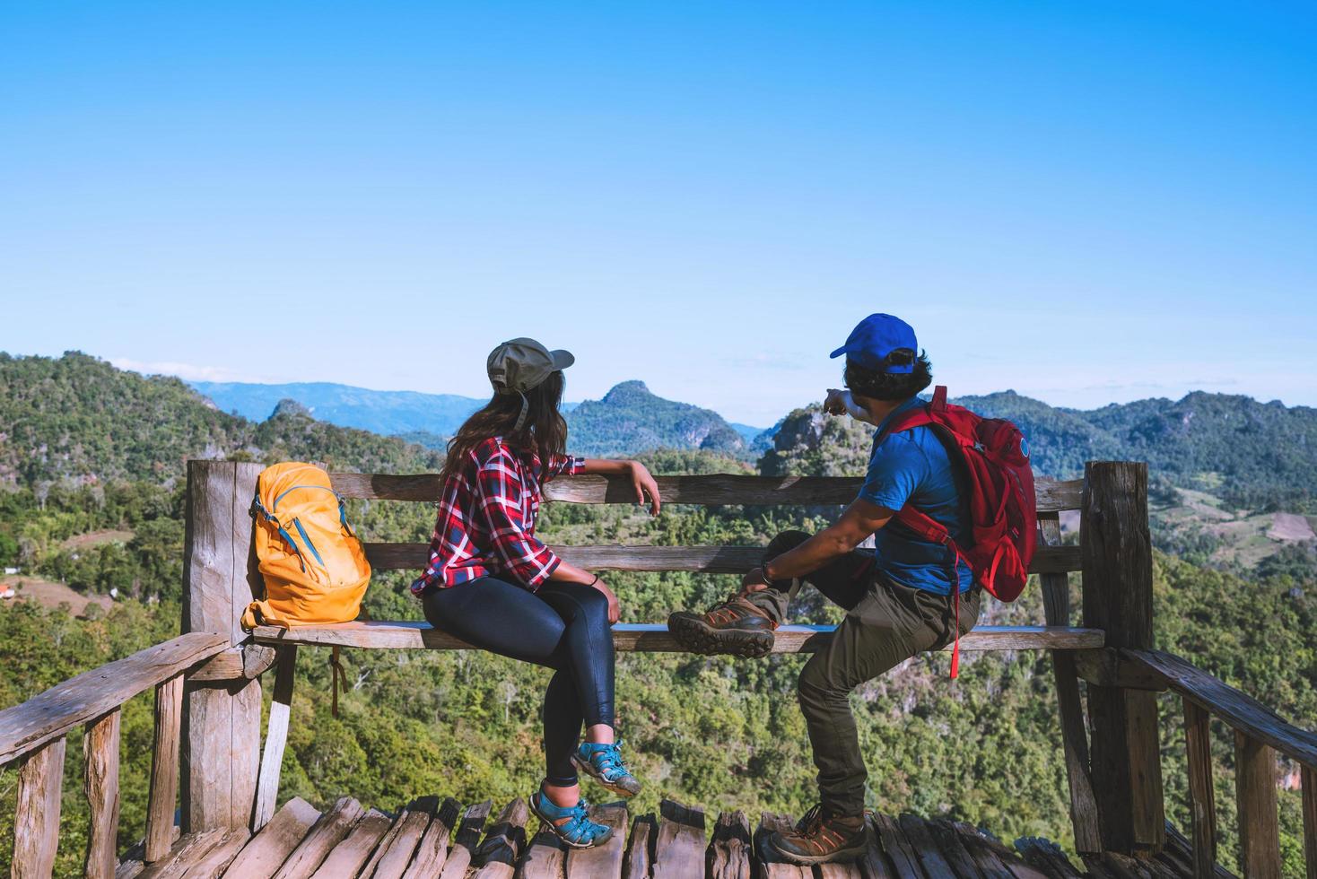 turistas de casal asiático com mochilas felizes em viajar, ela levantou a mão para fazer um formato de coração e apreciar a paisagem natural da montanha. foto