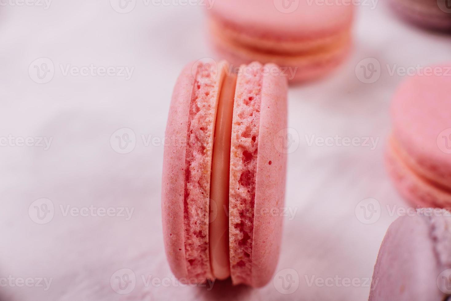 lindos macaroons saborosos cor de rosa em um fundo de concreto foto