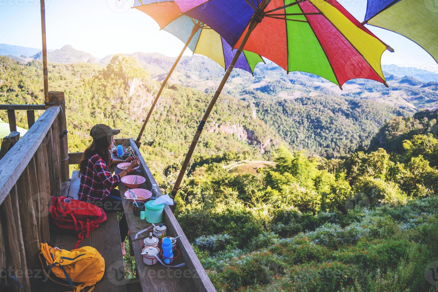 a garota sentada comendo macarrão na aldeia rural estilo pernas penduradas para o ponto de vista na montanha, as atrações locais da província de mae hong son na tailândia. foto