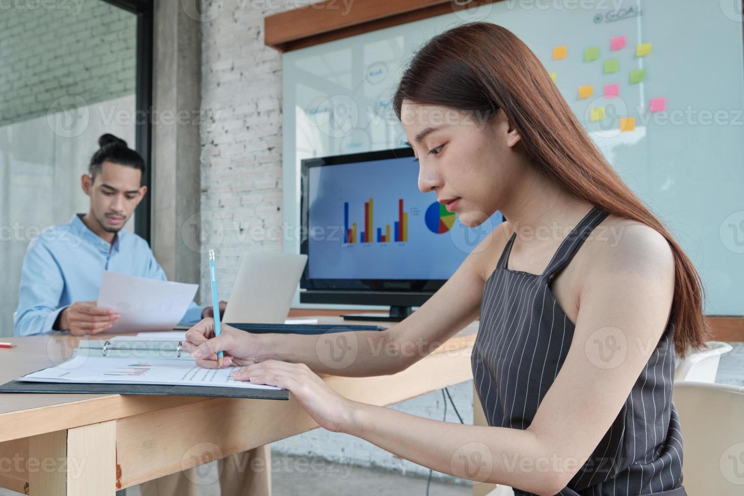 dois colegas e colegas de trabalho de etnia asiática e projeto de finanças de reunião discutem com gráficos de negócios em uma sala de conferências com papel colorido colado colado ao quadro no escritório. foto