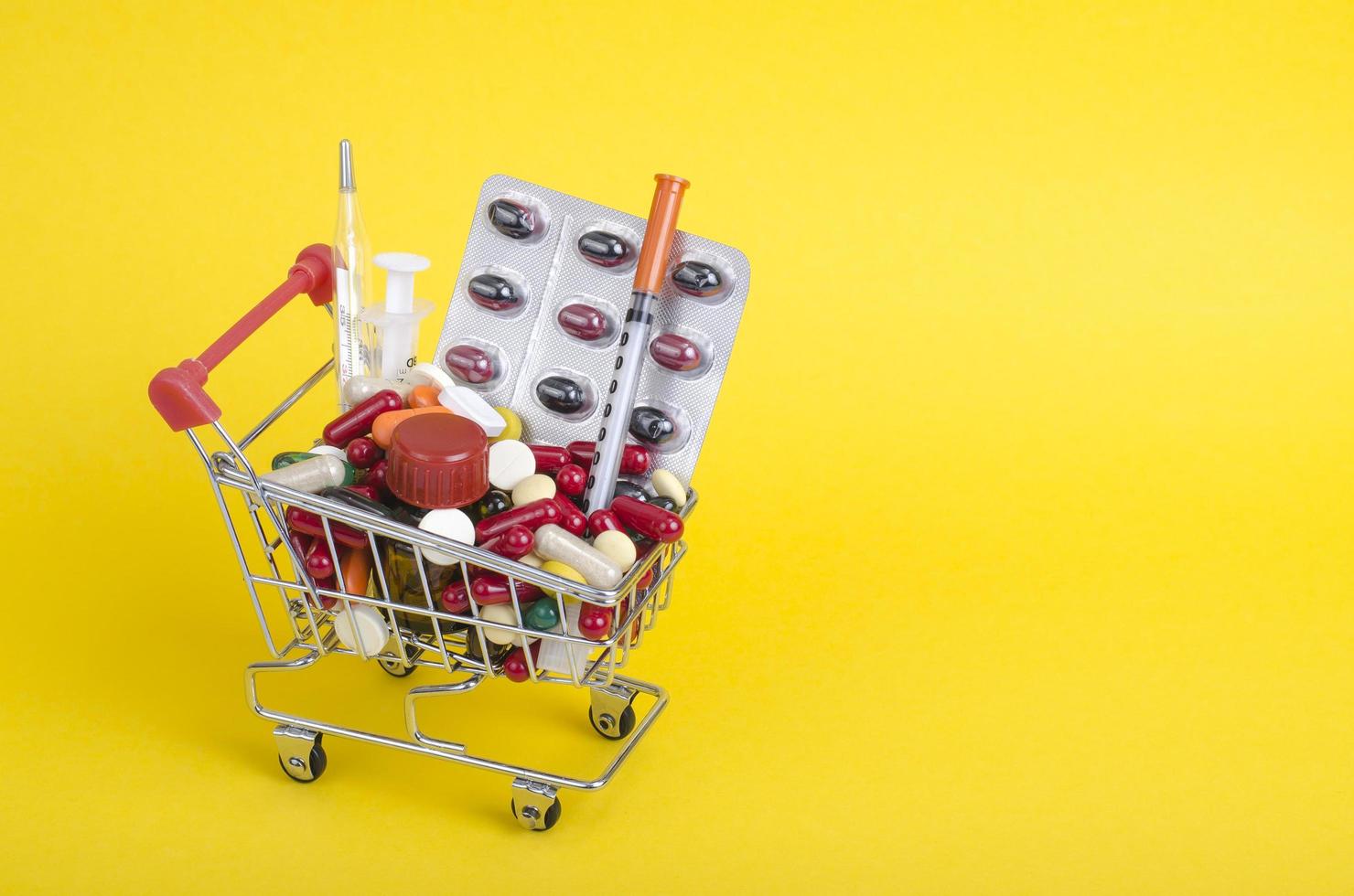 medicina e conceito de saúde. vários medicamentos no carrinho em fundo amarelo foto