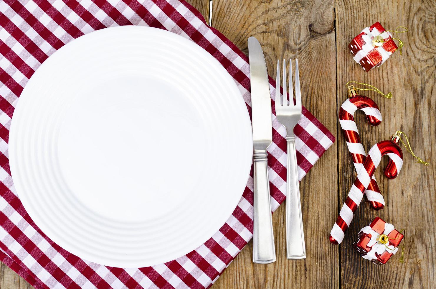 conceito de Natal e ano novo. prato branco, toalha de mesa vermelha. foto de estúdio