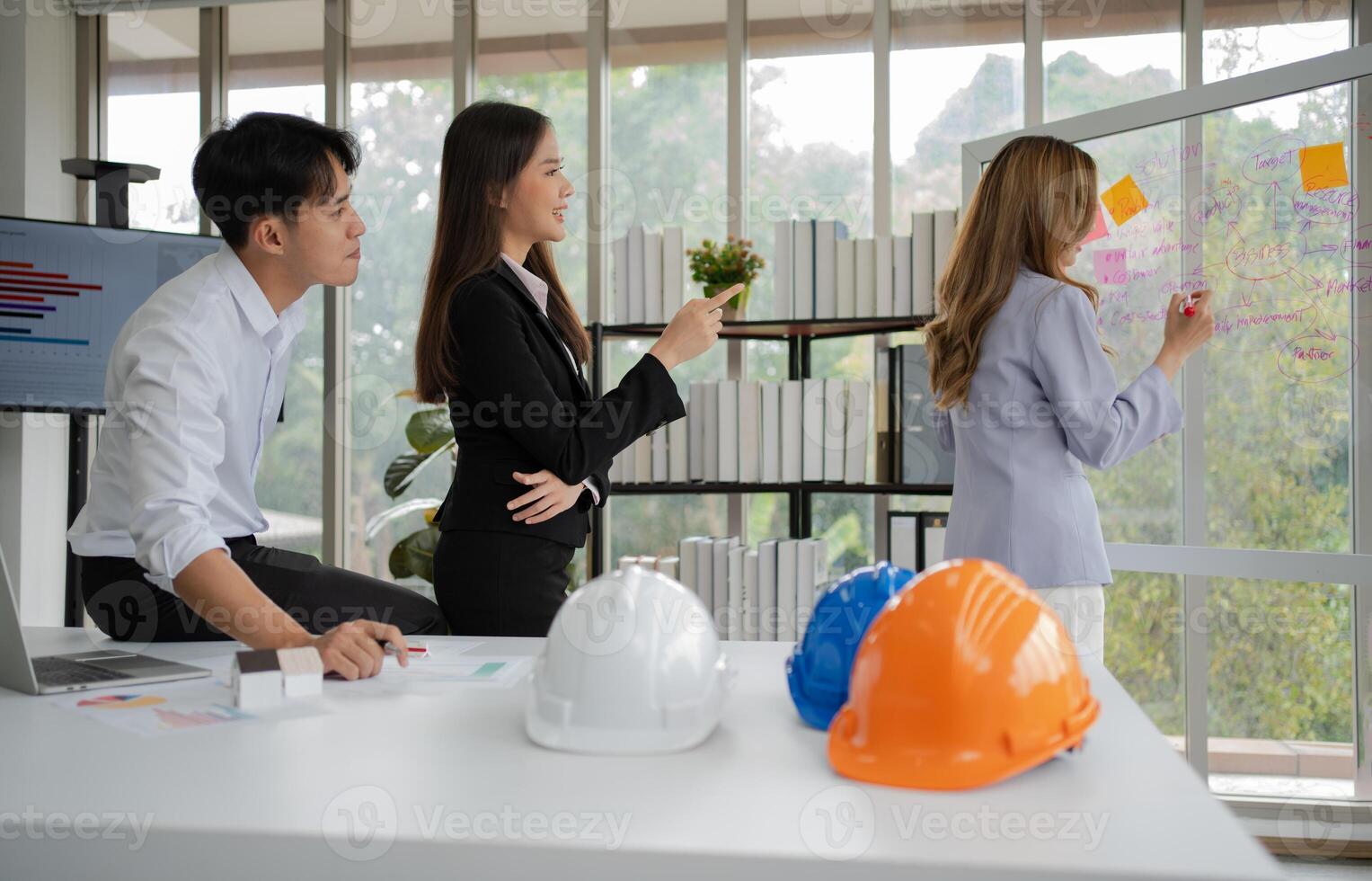 grupo do ásia pessoas de negócio e engenheiros trabalhando e debate dentro escritório. competente construção equipe tendo discussão durante reunião. equipe arquiteto olhando às plantas dentro uma construção local foto