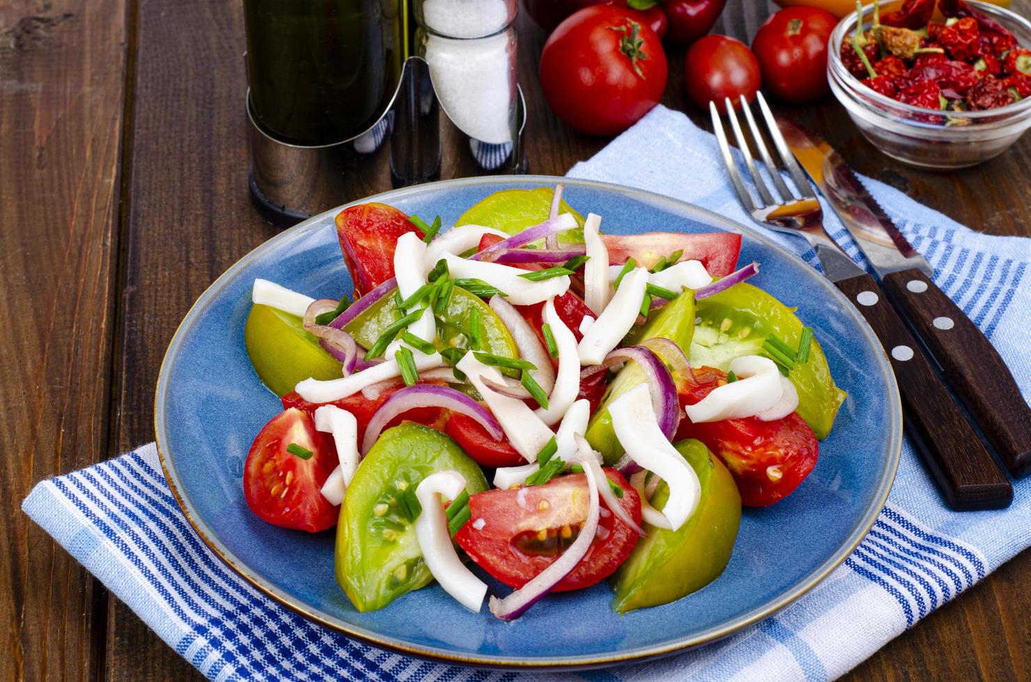 salada de legumes saudável com tomate e pedaços de lula. foto de estúdio.