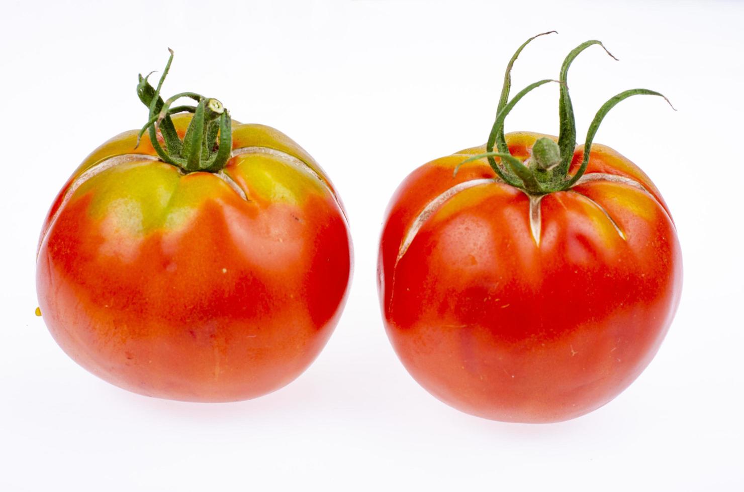 dois tomates vermelhos maduros com pele rachada. foto de estúdio.