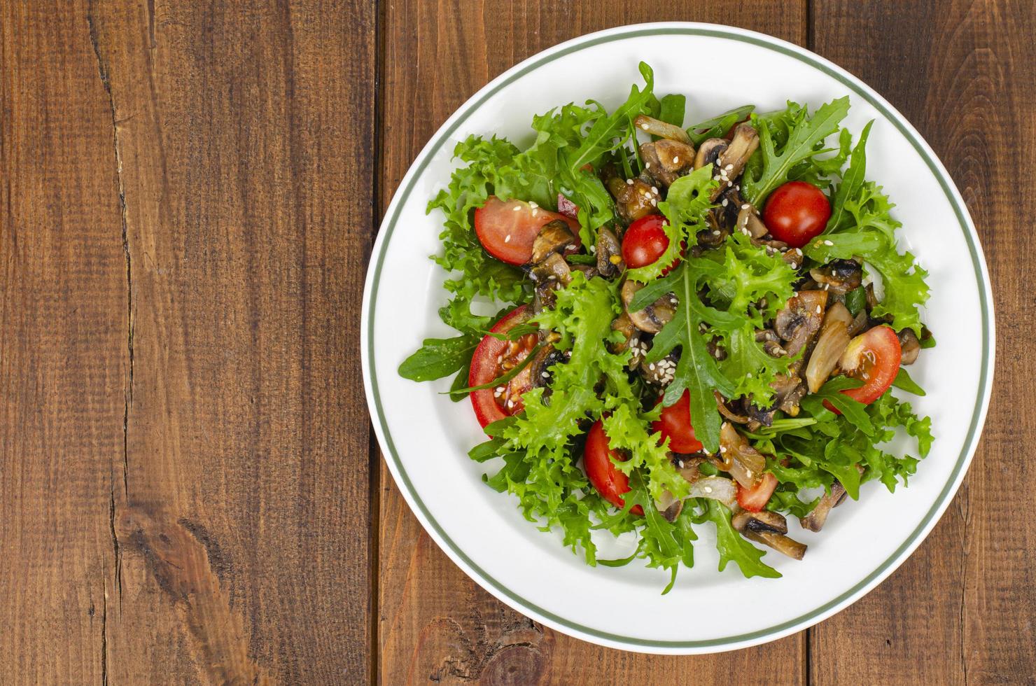 dieta salada de folhas de rúcula, tomate e cogumelos fritos na mesa de madeira. foto de estúdio